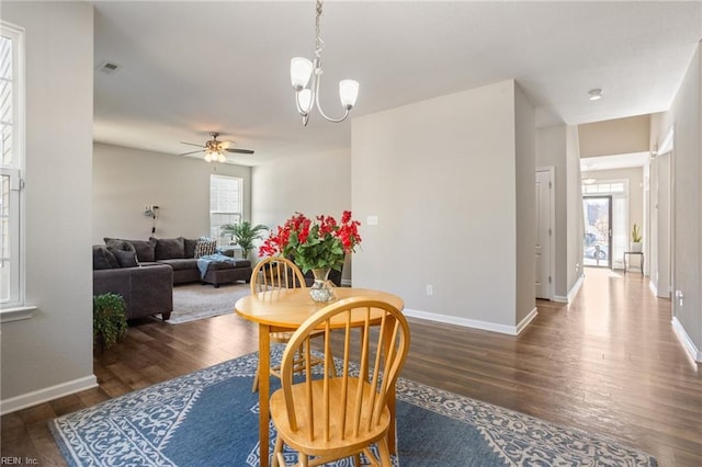 dining space with dark hardwood / wood-style floors and ceiling fan with notable chandelier