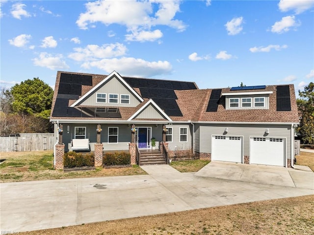 view of front facade with a porch, a garage, a front lawn, and solar panels