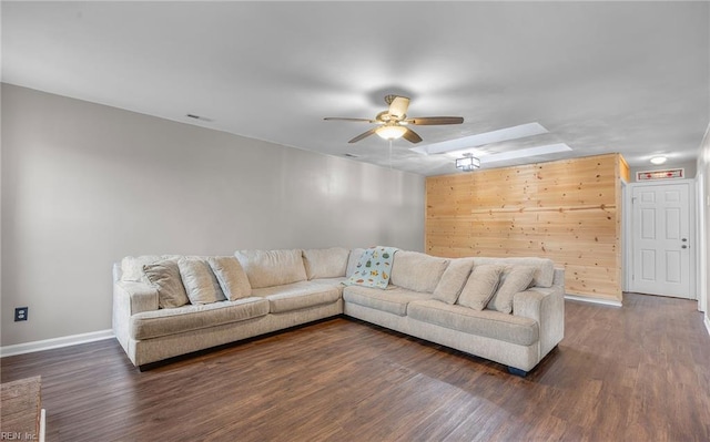 living room with dark hardwood / wood-style flooring, wooden walls, and ceiling fan