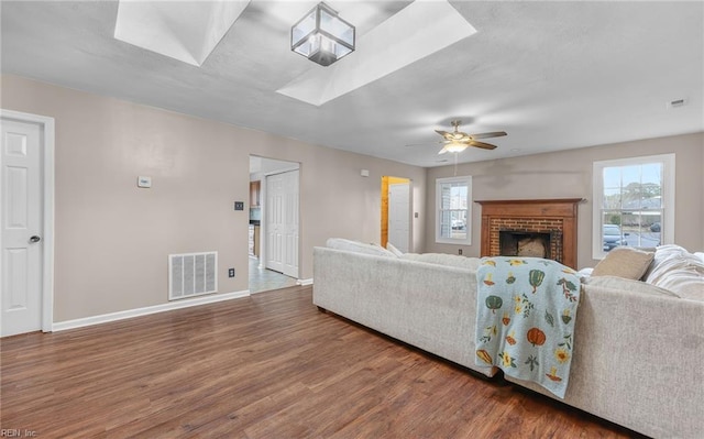 living room with ceiling fan, a healthy amount of sunlight, dark hardwood / wood-style flooring, and a skylight