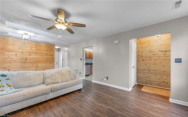 living room featuring ceiling fan, dark hardwood / wood-style flooring, and wood walls