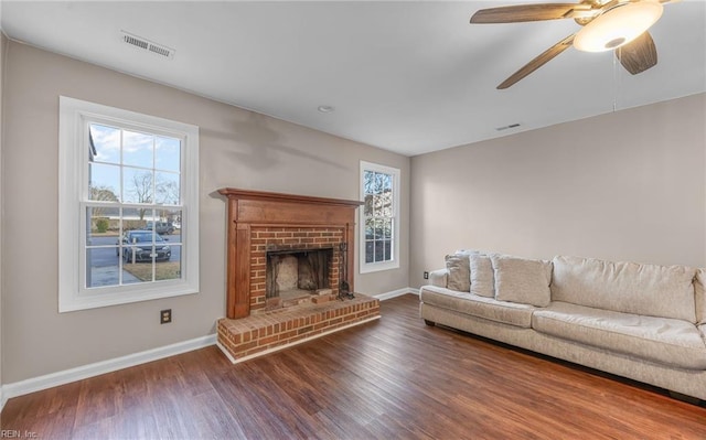 living room featuring ceiling fan, plenty of natural light, dark hardwood / wood-style flooring, and a brick fireplace