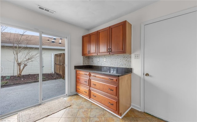 kitchen with tasteful backsplash, light tile patterned flooring, and dark stone countertops