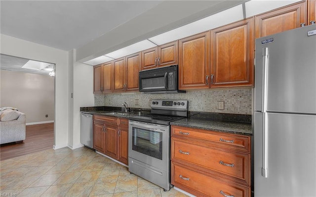 kitchen with dark stone countertops, sink, tasteful backsplash, and stainless steel appliances