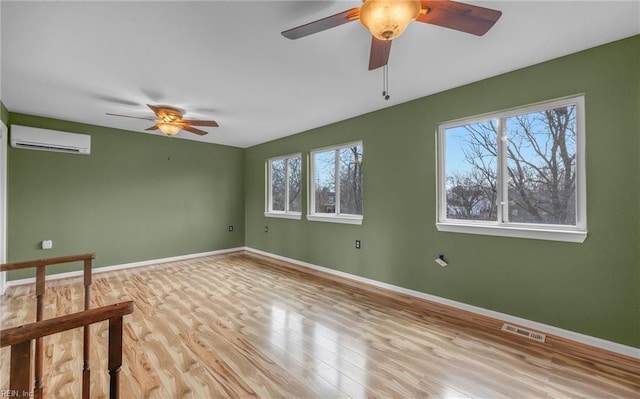 spare room featuring ceiling fan, a wall mounted AC, and light hardwood / wood-style flooring