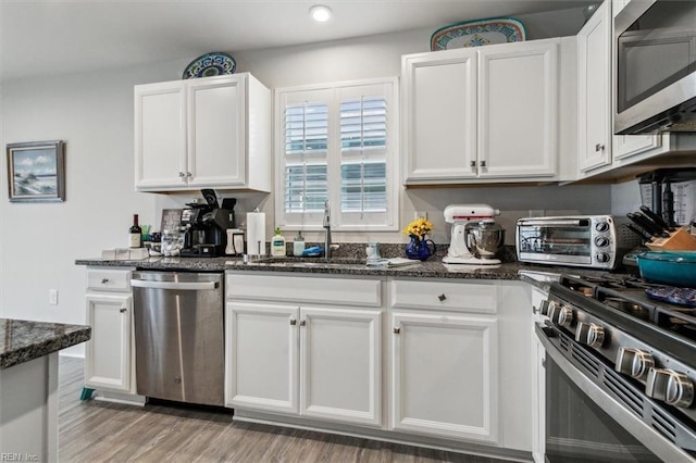 kitchen with dark stone countertops, sink, white cabinets, and appliances with stainless steel finishes