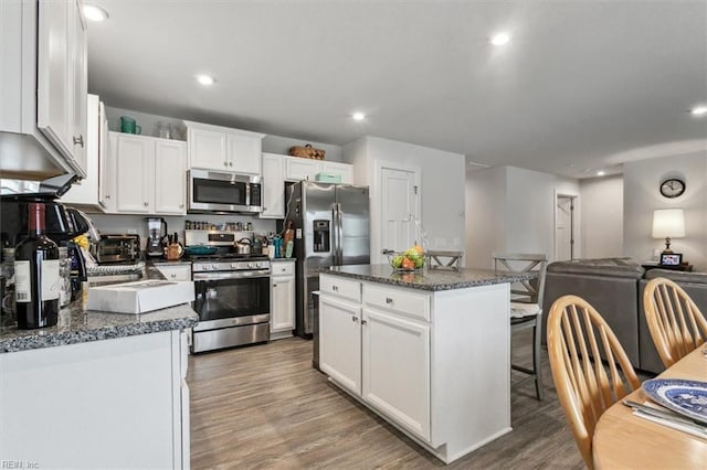 kitchen featuring dark stone countertops, appliances with stainless steel finishes, a center island, and white cabinets