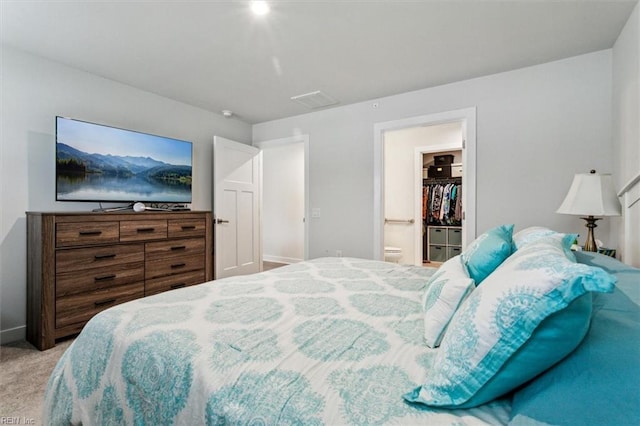 bedroom with ensuite bathroom and light carpet