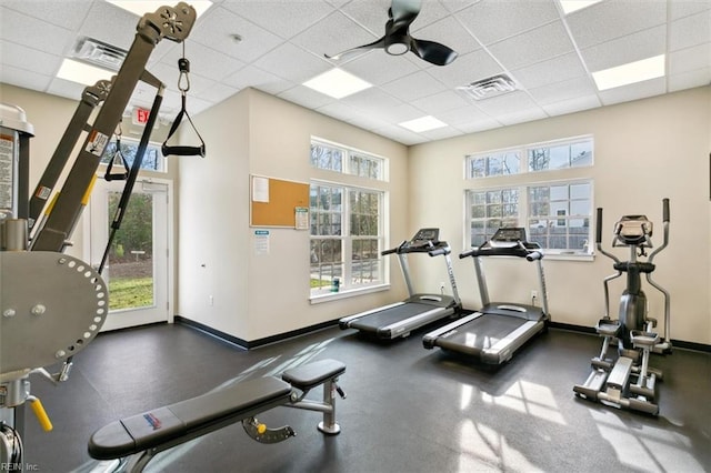 gym with ceiling fan, plenty of natural light, and a drop ceiling