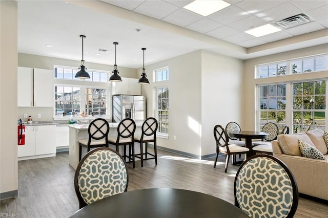 dining area with a healthy amount of sunlight, dark hardwood / wood-style flooring, a high ceiling, and a drop ceiling