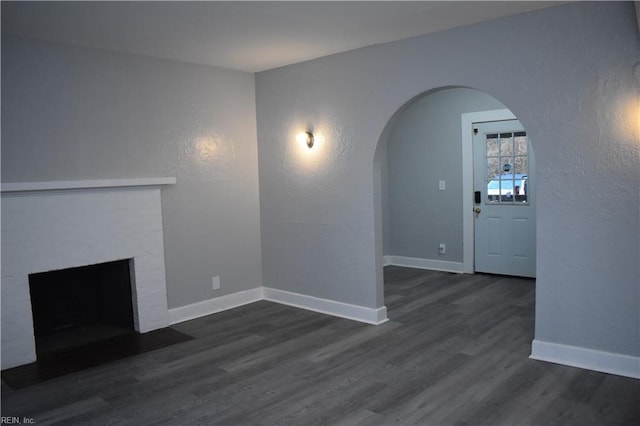 unfurnished living room with dark hardwood / wood-style floors and a brick fireplace