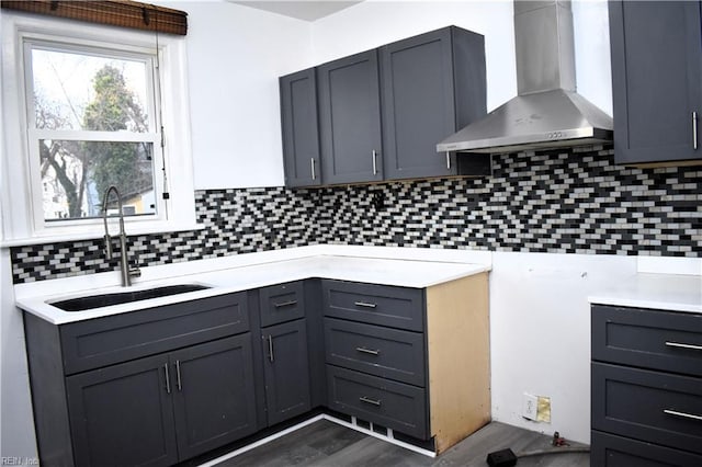 kitchen with gray cabinetry, sink, backsplash, and wall chimney exhaust hood