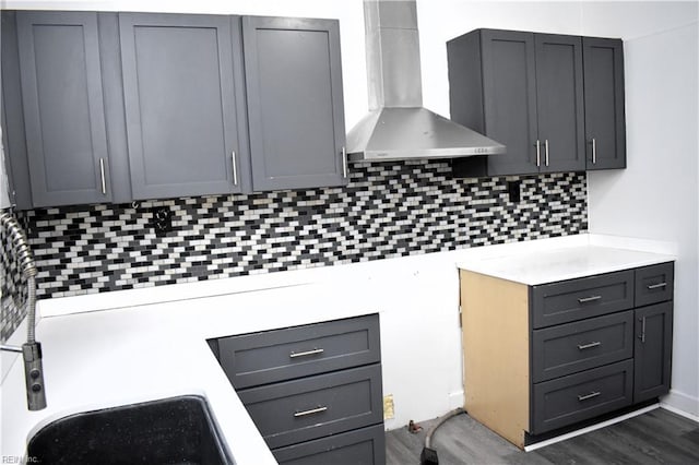 kitchen featuring gray cabinetry, backsplash, dark hardwood / wood-style flooring, and wall chimney exhaust hood