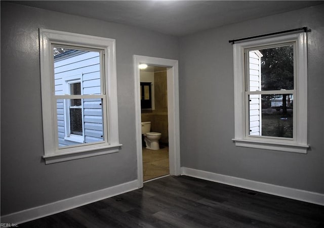 unfurnished bedroom with ensuite bath and dark hardwood / wood-style floors