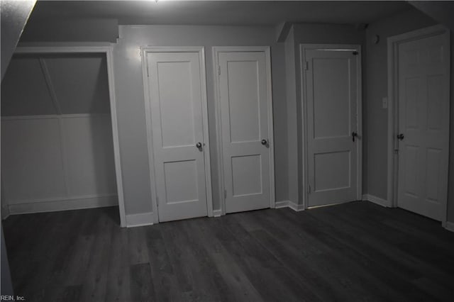 unfurnished bedroom featuring dark wood-type flooring and two closets