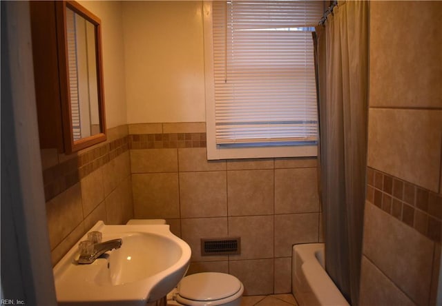 full bathroom featuring tile walls, sink, toilet, and shower / bath combo with shower curtain