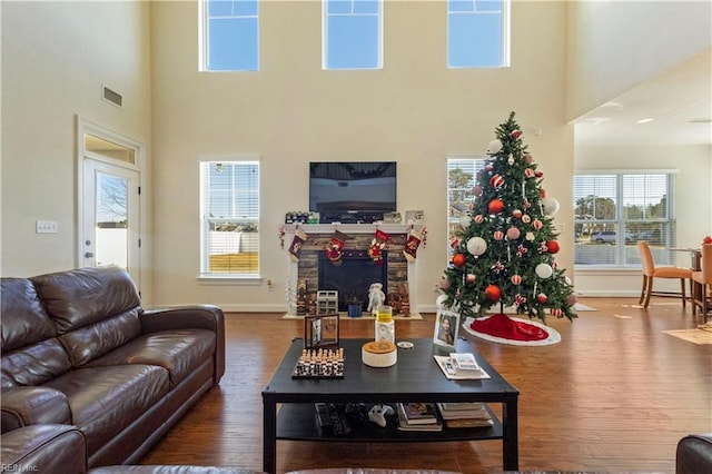 living room featuring hardwood / wood-style flooring, a fireplace, and a high ceiling