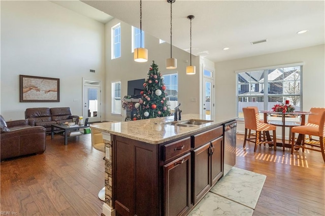 kitchen featuring light stone countertops, sink, light hardwood / wood-style flooring, and decorative light fixtures