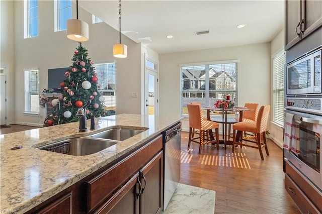 kitchen featuring pendant lighting, sink, appliances with stainless steel finishes, dark hardwood / wood-style floors, and light stone countertops