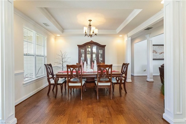 dining space with a notable chandelier, dark hardwood / wood-style flooring, a raised ceiling, and ornate columns