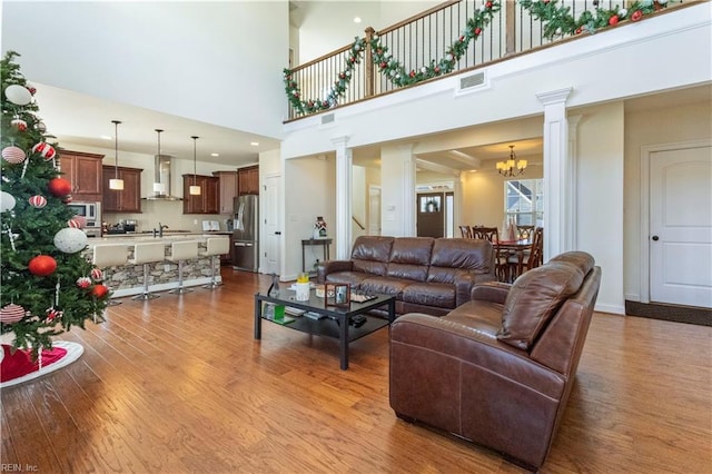 living room featuring an inviting chandelier, sink, light hardwood / wood-style flooring, and ornate columns