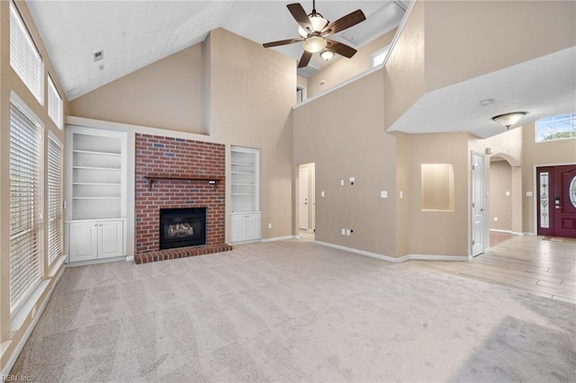 unfurnished living room featuring high vaulted ceiling, a fireplace, light colored carpet, ceiling fan, and built in shelves