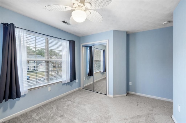 unfurnished bedroom featuring light carpet, ceiling fan, and a closet