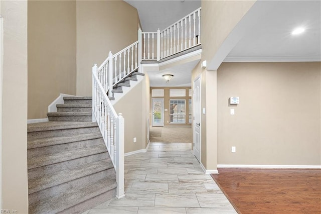 entryway with crown molding and a towering ceiling