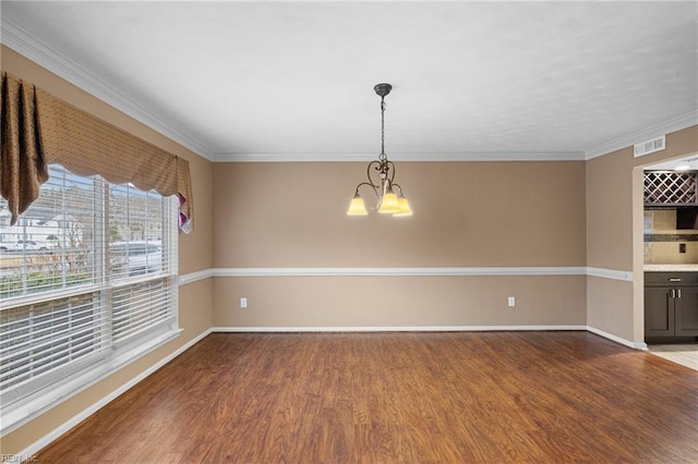 unfurnished room featuring an inviting chandelier, hardwood / wood-style flooring, and crown molding