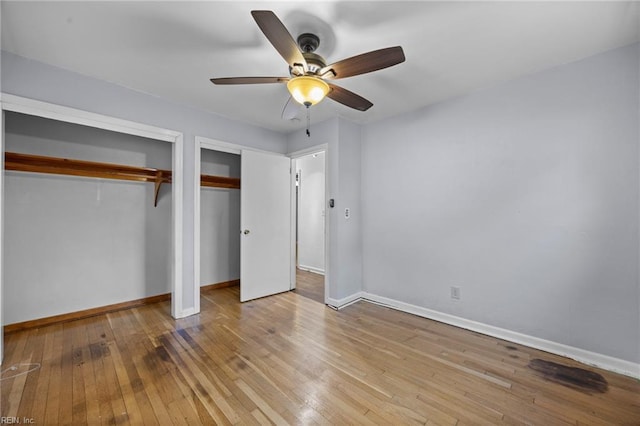 unfurnished bedroom featuring multiple closets, ceiling fan, and light hardwood / wood-style floors