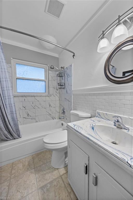 full bathroom featuring shower / bath combo, tile walls, vanity, and toilet