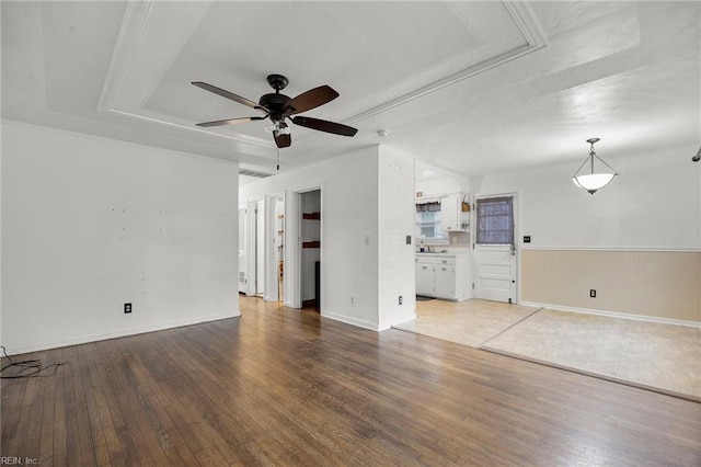 unfurnished living room with hardwood / wood-style flooring, ceiling fan, and a tray ceiling