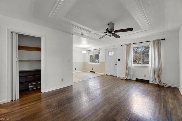 unfurnished living room with plenty of natural light, dark hardwood / wood-style floors, ceiling fan, and a tray ceiling