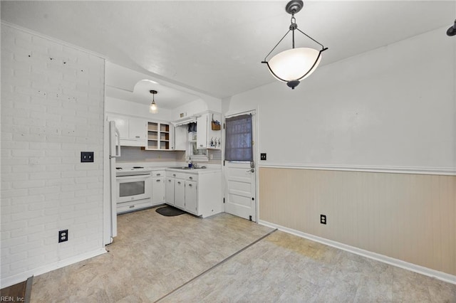 kitchen featuring sink, white appliances, white cabinetry, hanging light fixtures, and brick wall