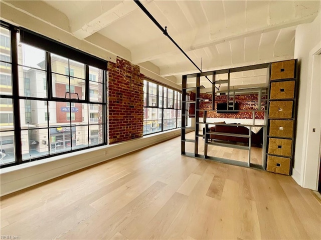 bedroom with wood-type flooring, beamed ceiling, and brick wall