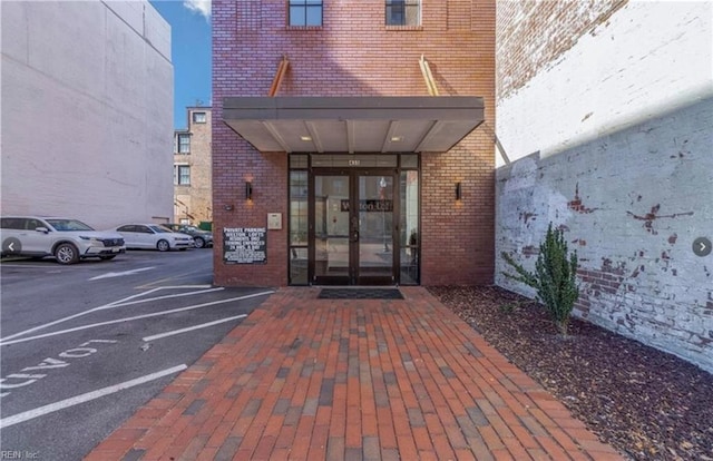 doorway to property with uncovered parking, french doors, and brick siding