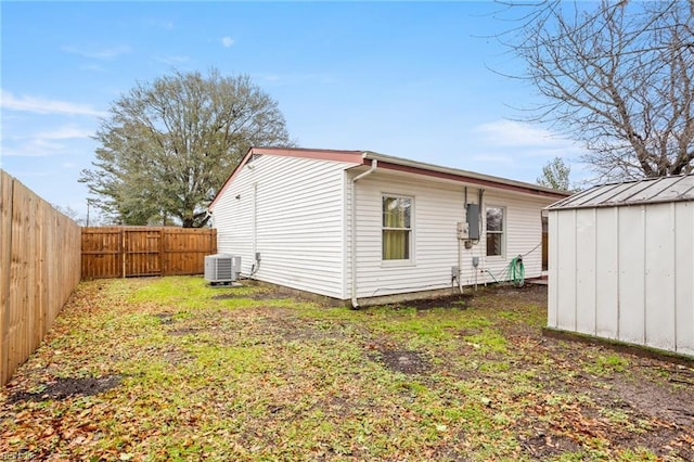 rear view of house with a lawn, central AC unit, and a storage unit