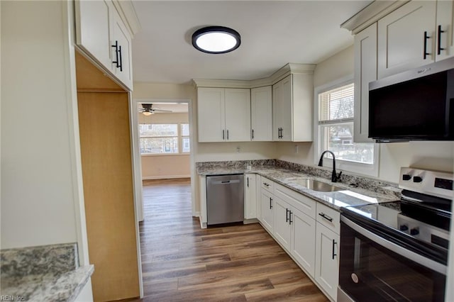 kitchen featuring light stone counters, stainless steel appliances, sink, and a wealth of natural light