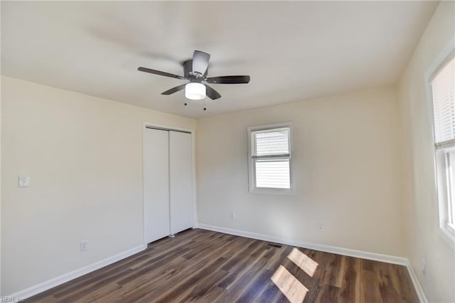 unfurnished bedroom with ceiling fan, dark hardwood / wood-style floors, and a closet