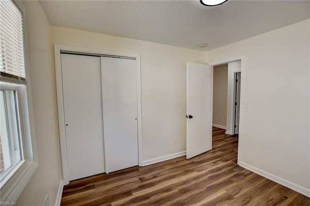 unfurnished bedroom with multiple windows, dark hardwood / wood-style floors, and a closet