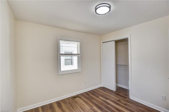 unfurnished bedroom with dark hardwood / wood-style floors and a closet