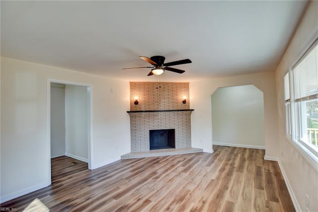 unfurnished living room featuring ceiling fan, light wood-type flooring, and a fireplace