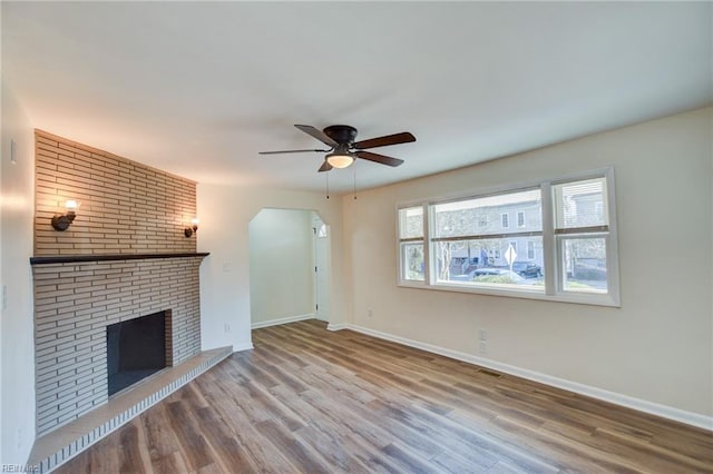 unfurnished living room with hardwood / wood-style flooring, ceiling fan, and a fireplace