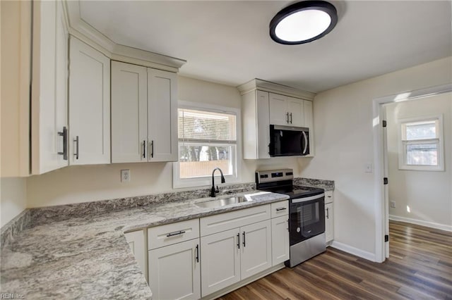 kitchen with sink, stainless steel appliances, light stone counters, white cabinets, and dark hardwood / wood-style flooring