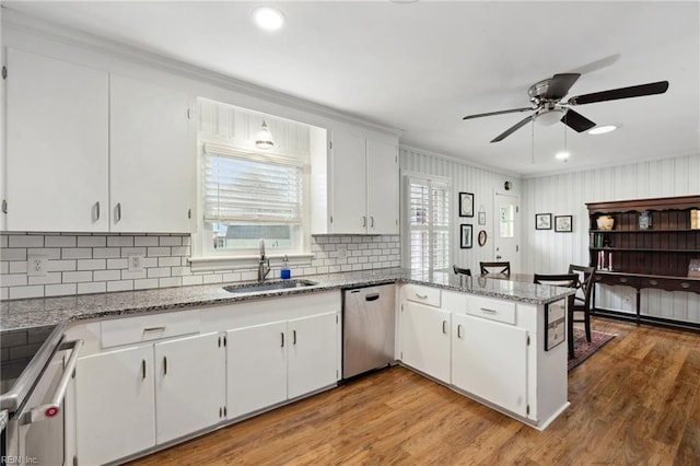 kitchen with appliances with stainless steel finishes, sink, white cabinets, and kitchen peninsula