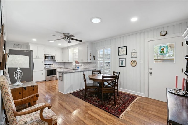 kitchen featuring light hardwood / wood-style flooring, white cabinetry, backsplash, stainless steel appliances, and kitchen peninsula