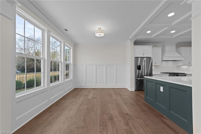 kitchen with crown molding, stainless steel fridge, custom range hood, and white cabinetry