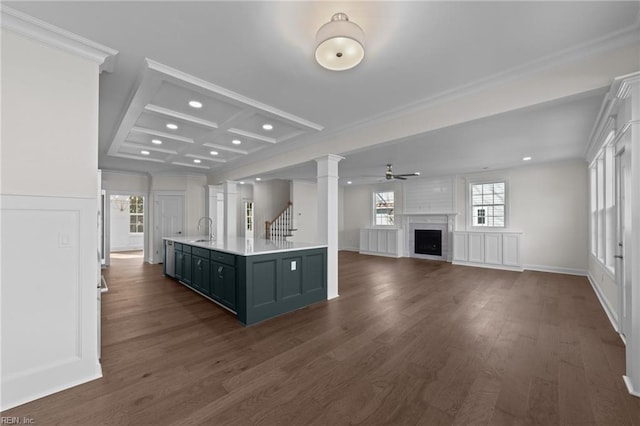 kitchen featuring a fireplace, a ceiling fan, light countertops, dark wood finished floors, and ornate columns