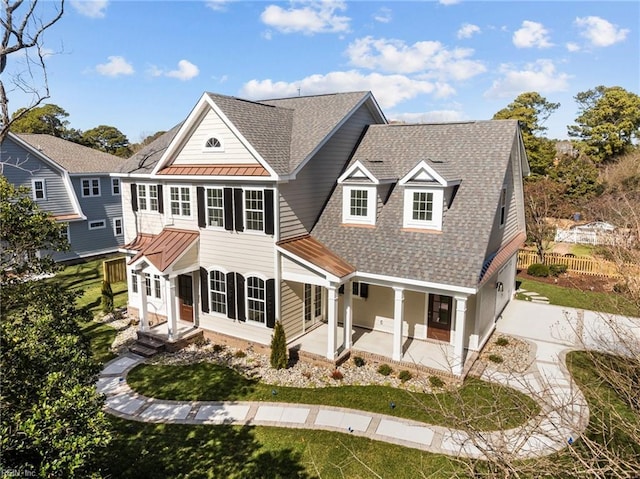 shingle-style home with metal roof, a patio, fence, roof with shingles, and a standing seam roof