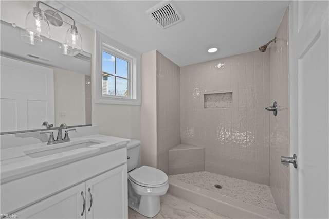 full bath with visible vents, a tile shower, vanity, and toilet